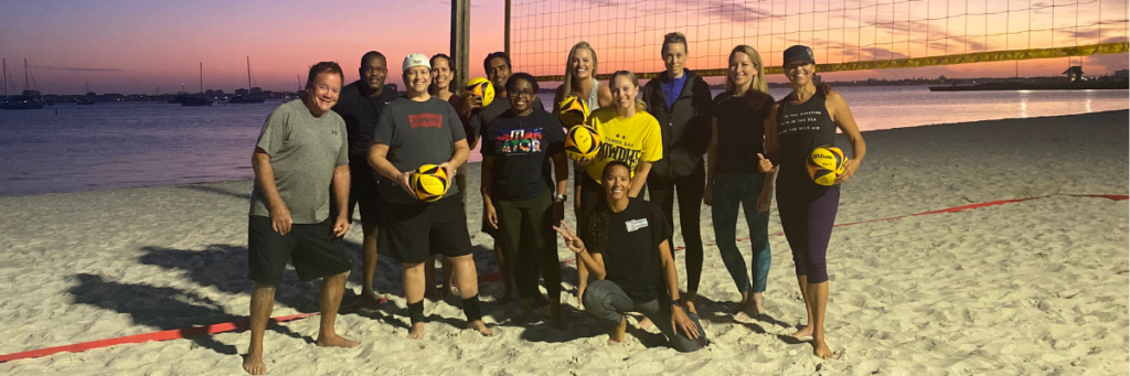 after volleyball 101 by volleyball solutions people smiling on a beach at sunset